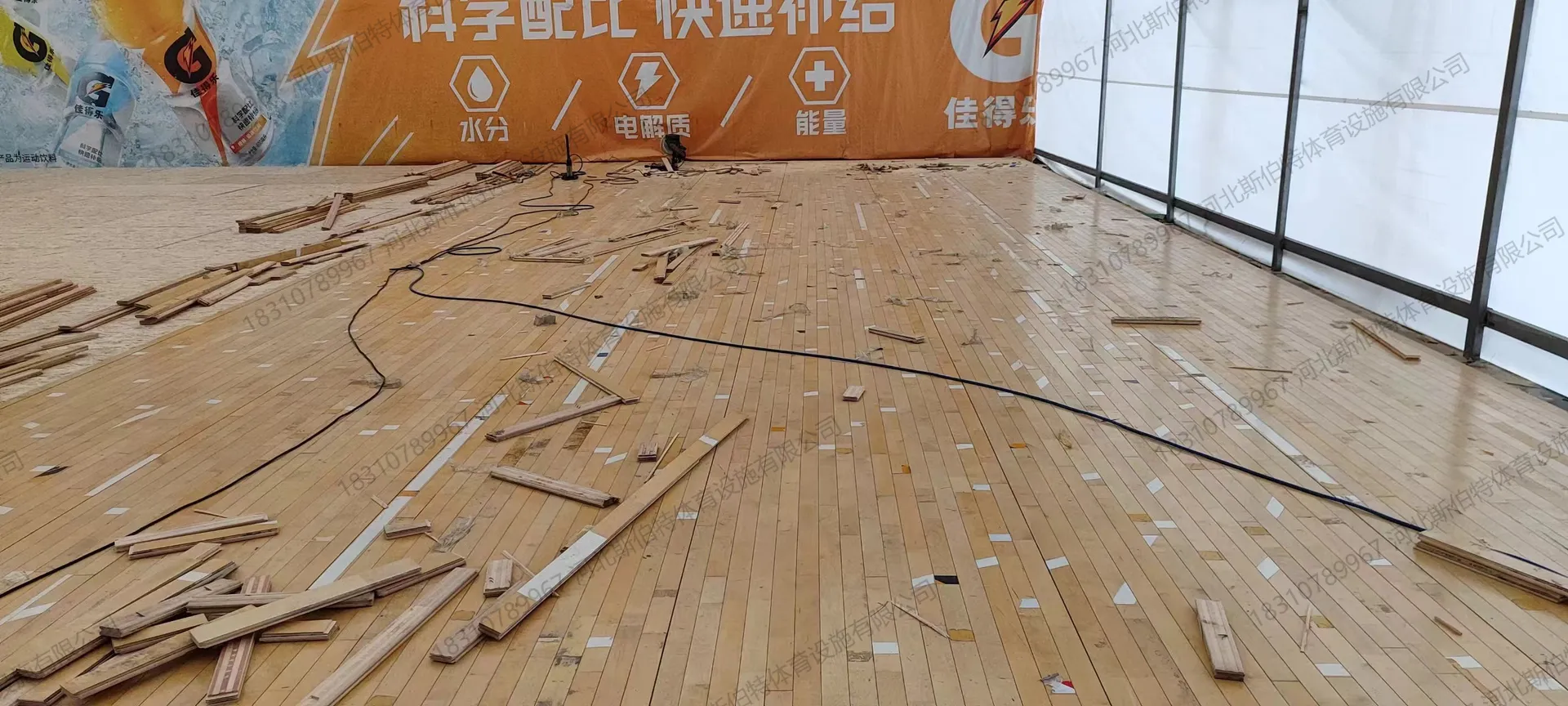 完工图：绿色PVC地胶+浅色实木地板拼接，红色广告墙