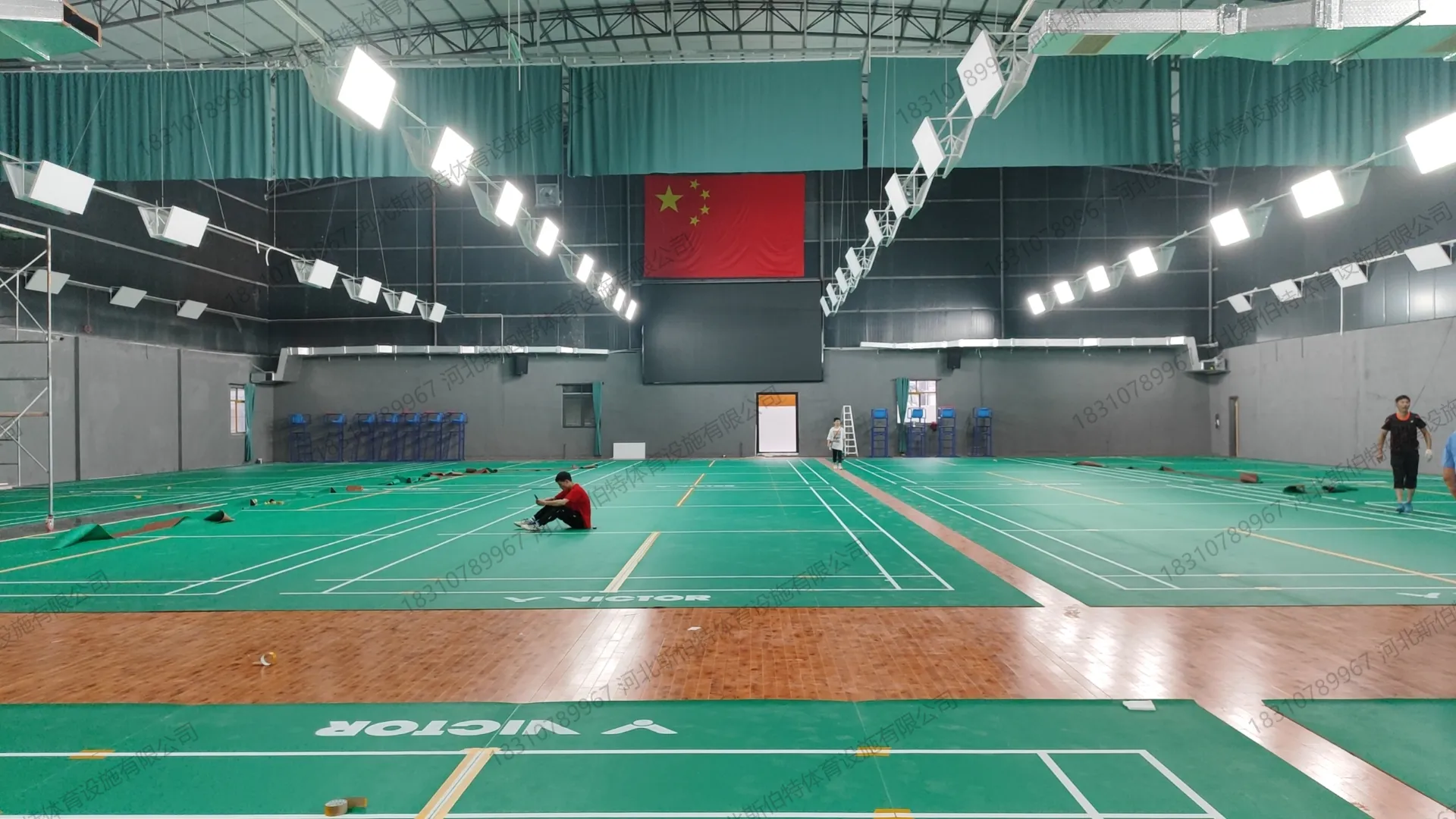 完工实景：羽毛球馆区VICTOR绿色PVC地胶，多片场地并列，国旗悬挂