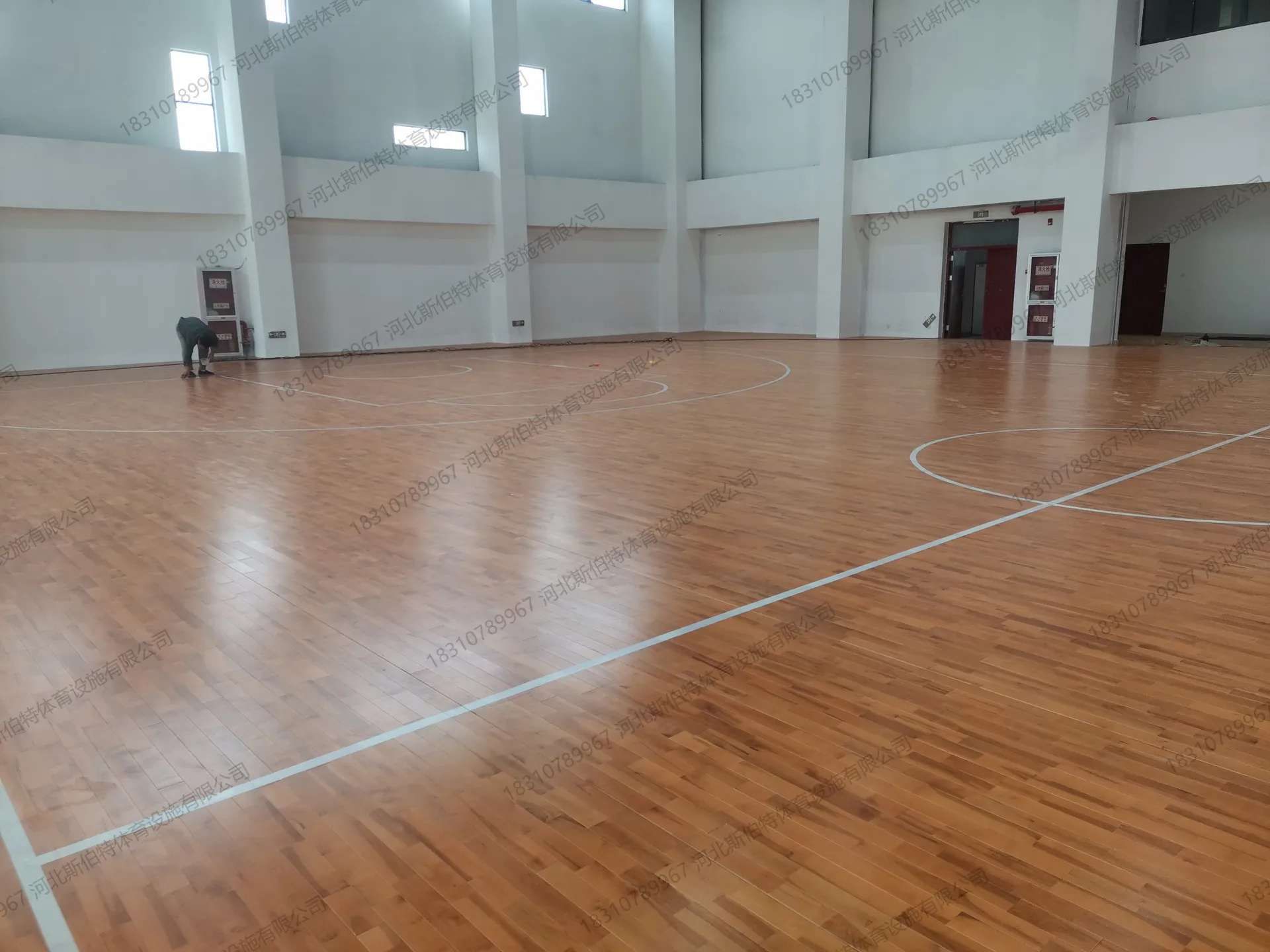 完工实景:篮球场标线完整,白色墙面,红色消防门,高窗采光