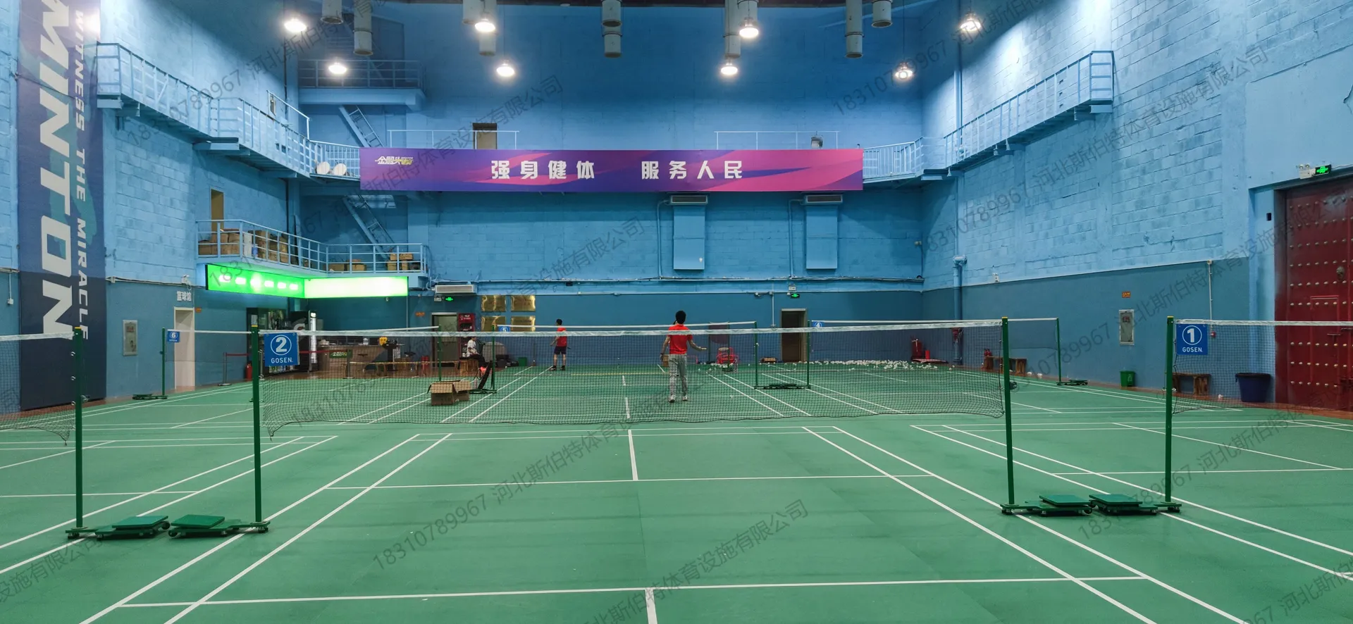 完工实景:羽毛球区,蓝色墙面"BADMINTON"竖幅,多块场地