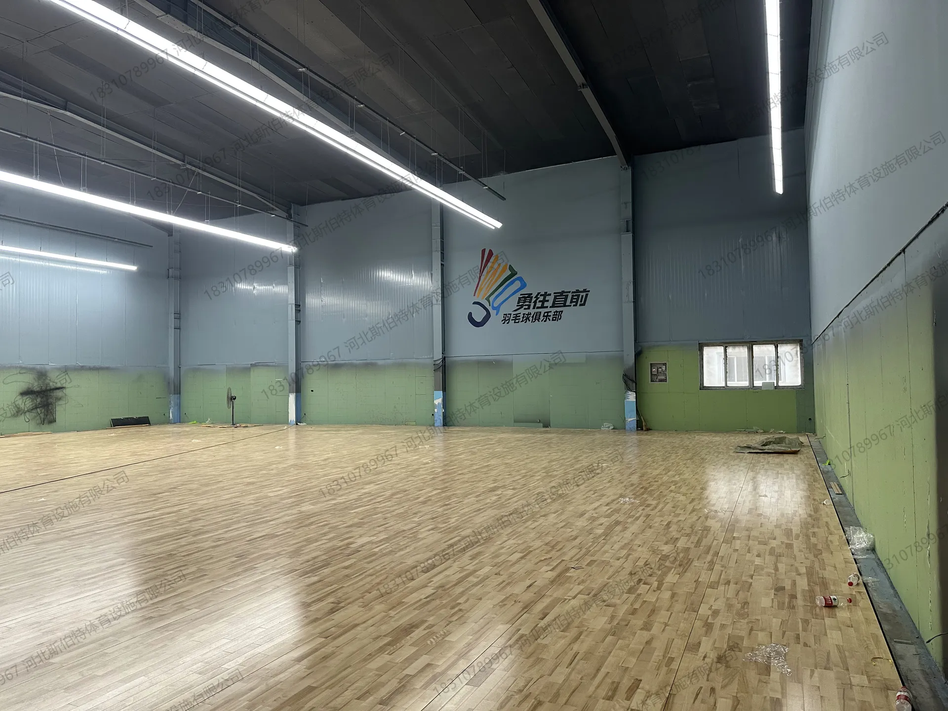 完工实景：枫桦木B级地板铺装完成，墙上有俱乐部Logo