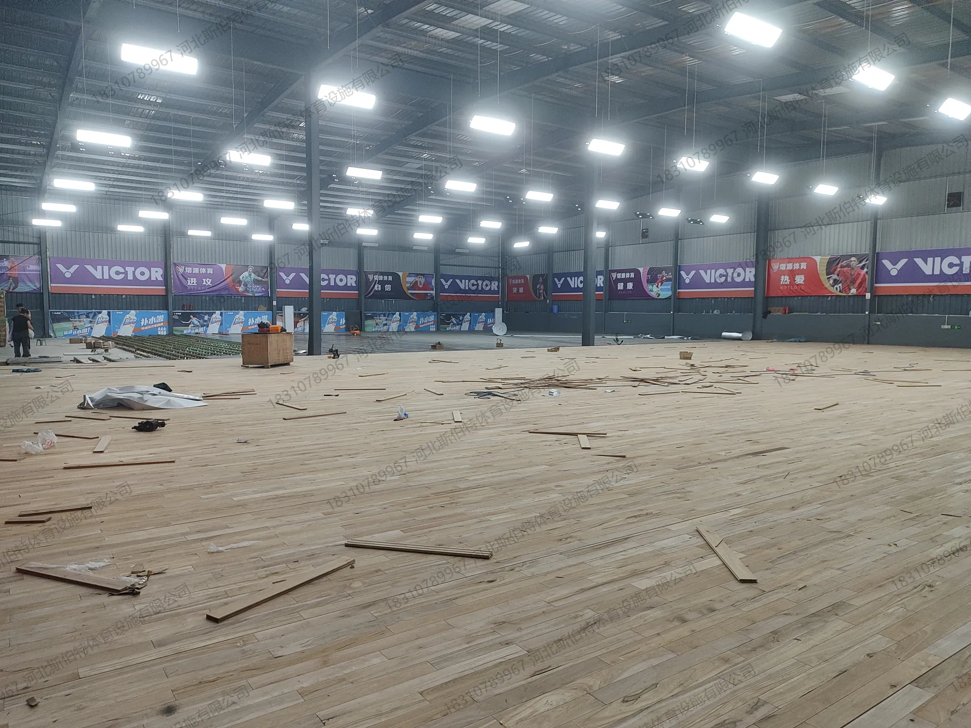 施工过程：面板大面积铺装中，地面散落未安装地板条，工人收尾作业