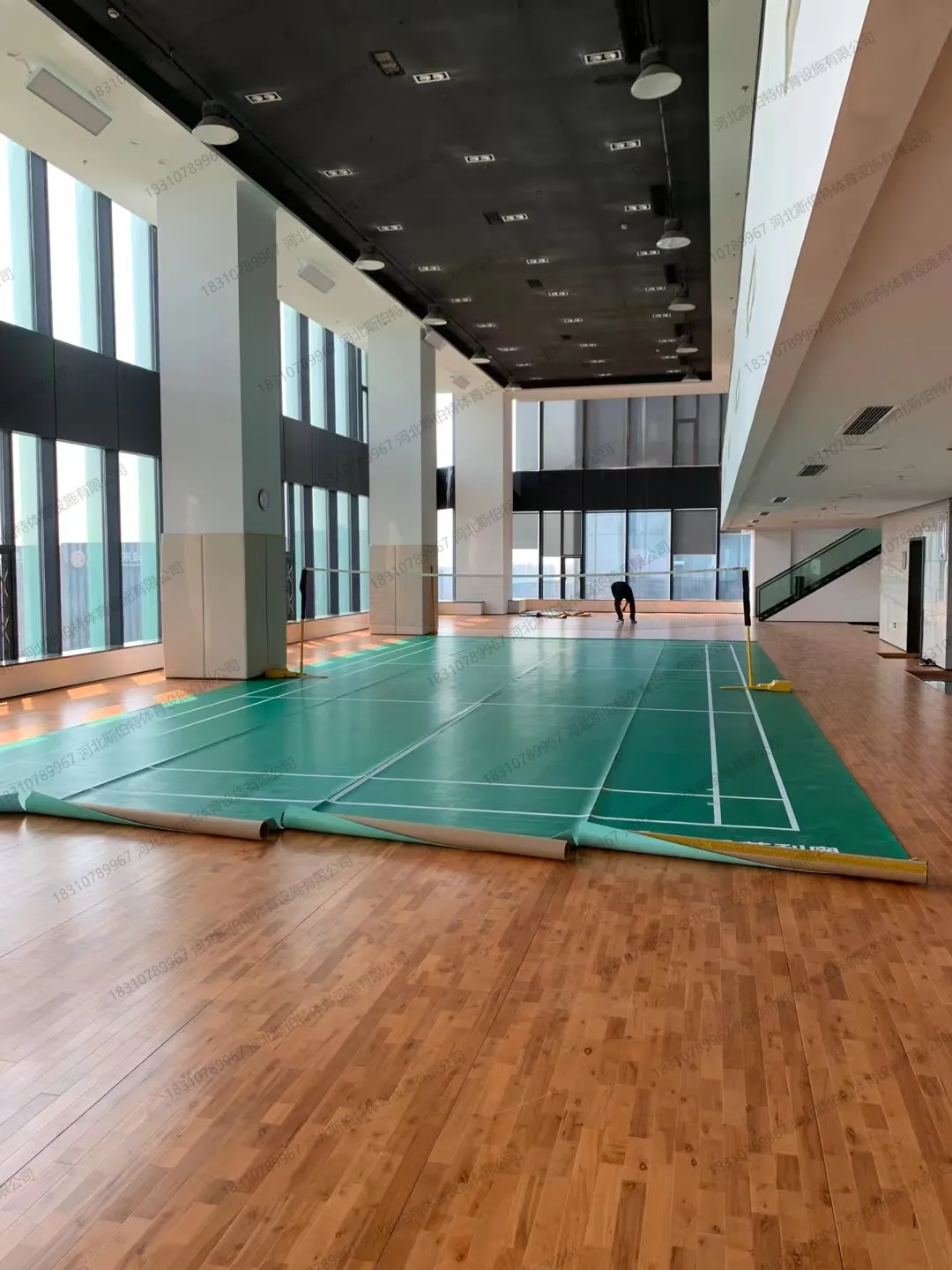 完工实景：羽毛球馆空间，二层平台带玻璃护栏，落地窗采光