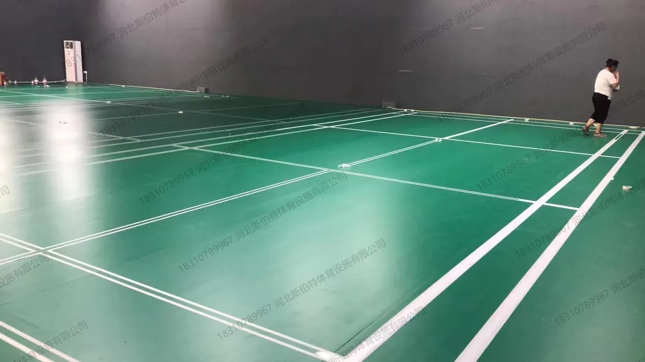 完工实景：绿色PVC地胶铺设完成，羽毛球场划线清晰，运动员训练中