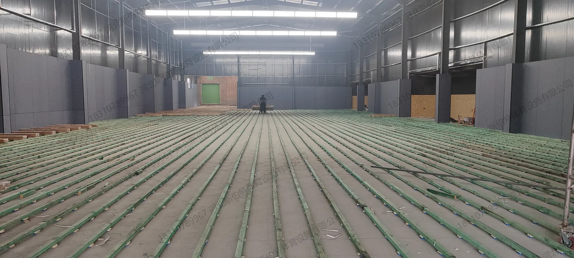 施工过程:板式龙骨铺设完成,绿色防腐木龙骨平行排列,减震垫分布其间