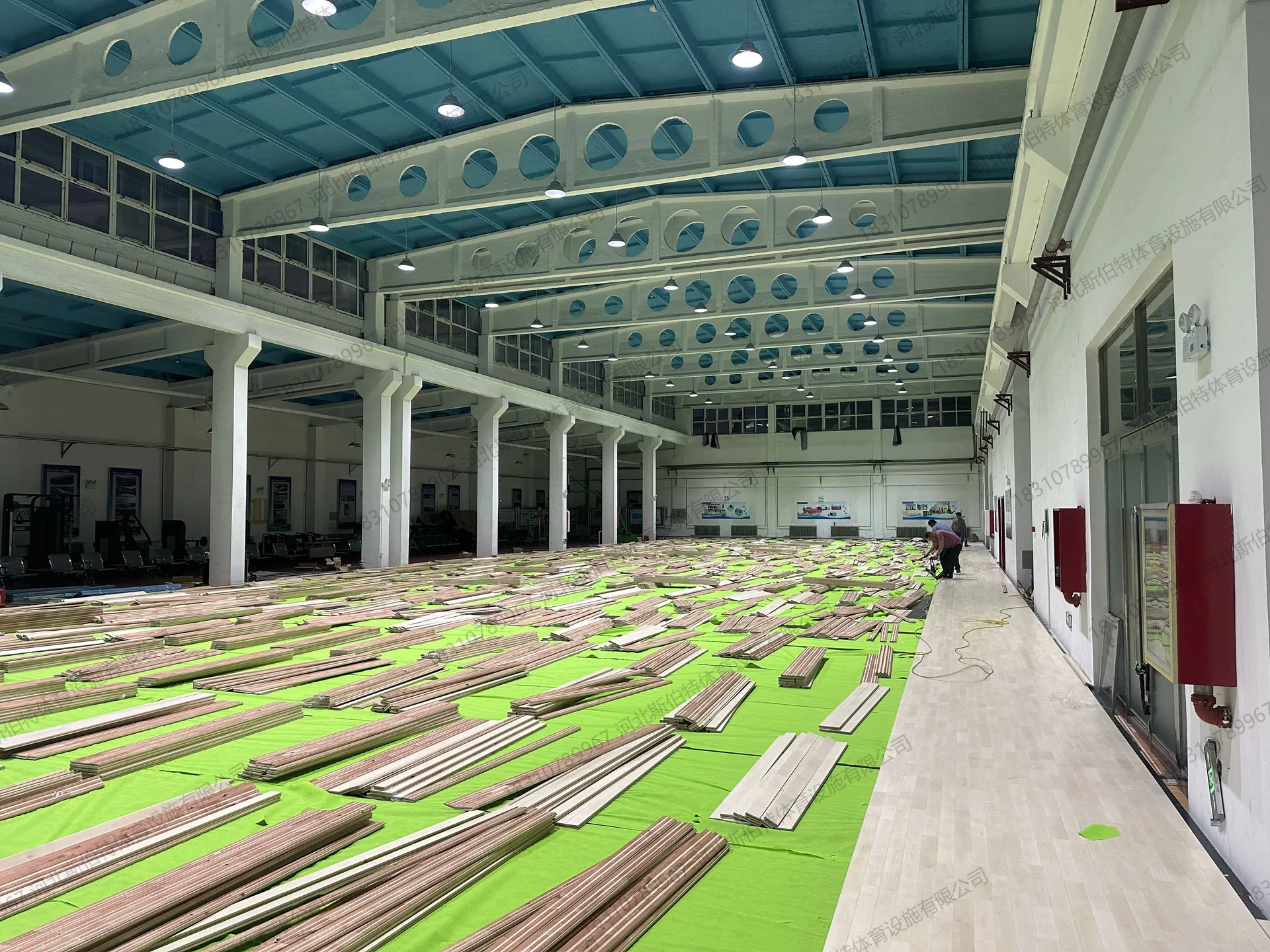 完工实景：木地板区乒乓球室，红双喜挡板围合，浅木色地板纹理细腻
