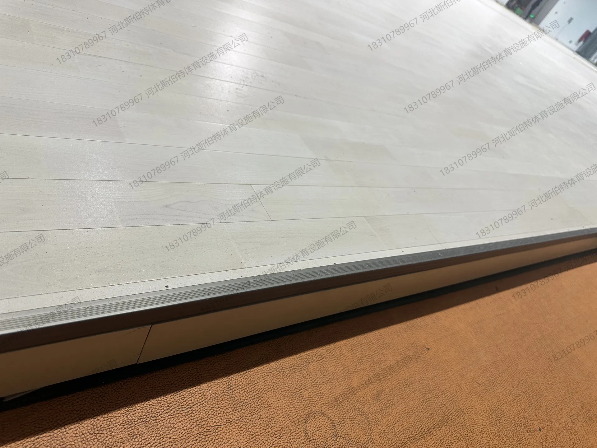 材料进场：夜间卸货，叉车搬运木地板材料，包装印有"体育工程专用"字样