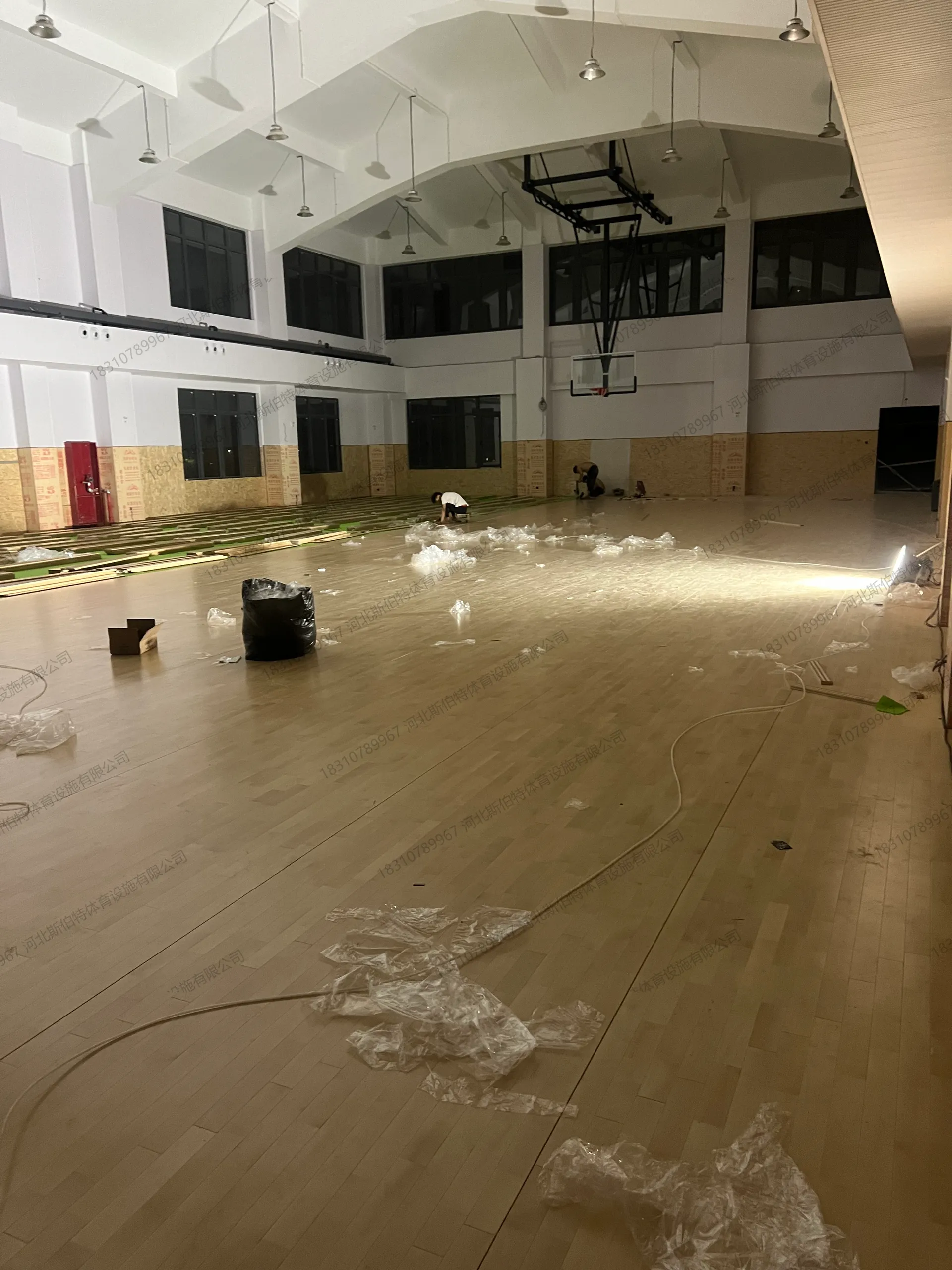 完工实景：枫桦木A级地板铺装完成，浅木色漆面，室内篮球馆空间