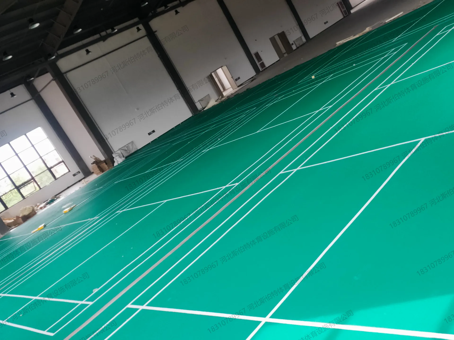 完工实景：室内体育馆绿色运动地胶铺设完成，白色场地标线已绘制