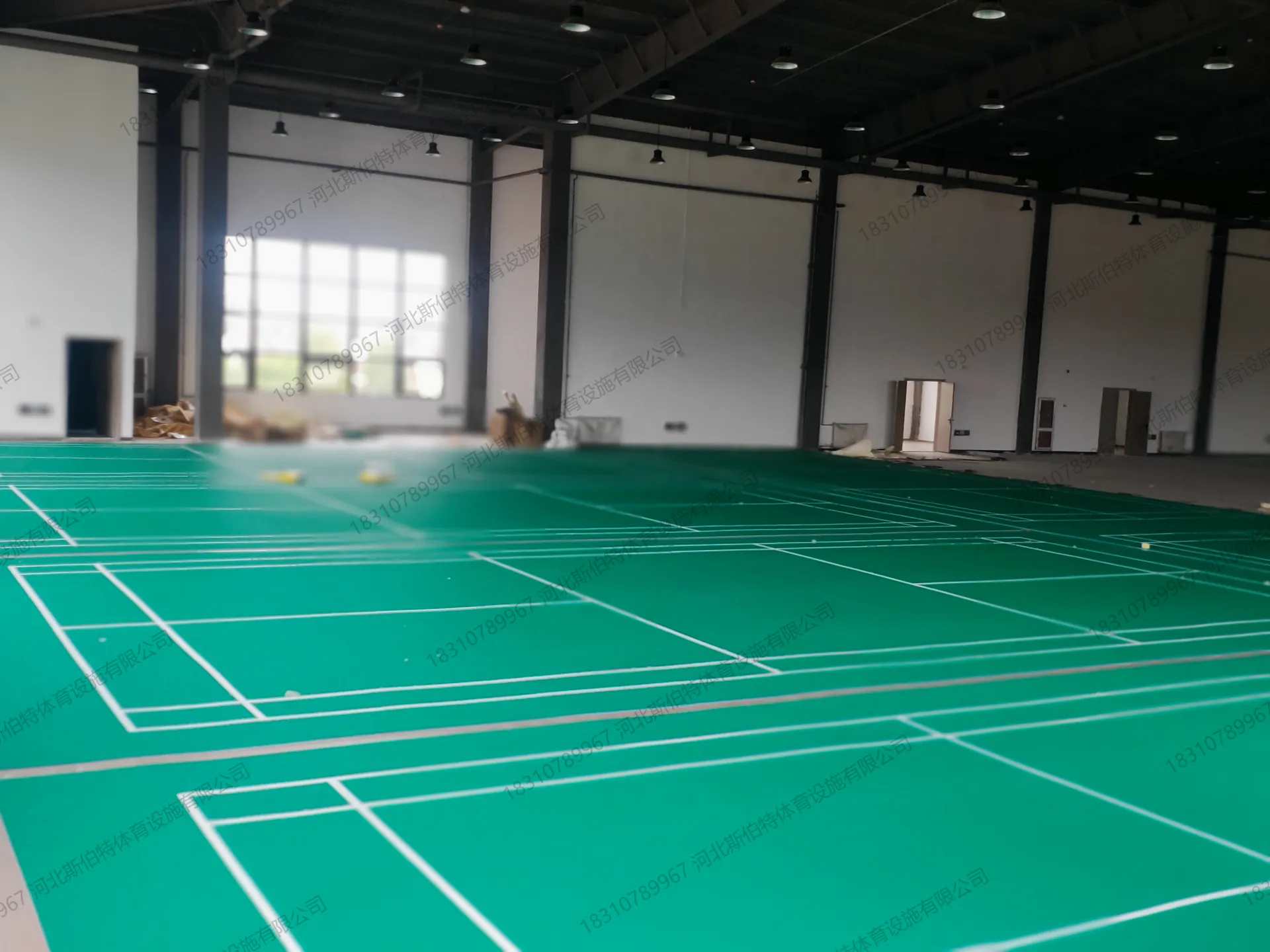 完工实景：室内羽毛球馆绿色PVC地胶铺设完毕，白色标线清晰