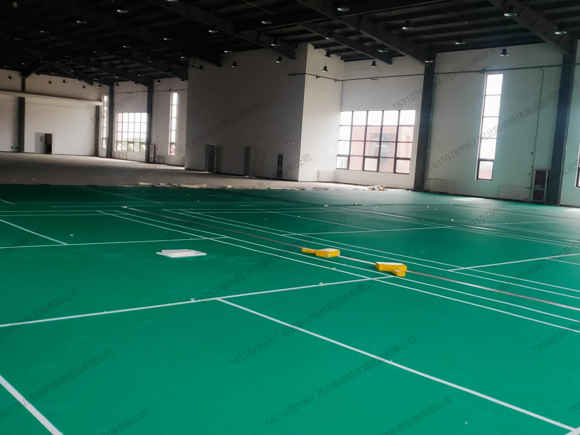 施工过程：室内场馆绿色地胶铺设阶段，画线初步完成，待收尾