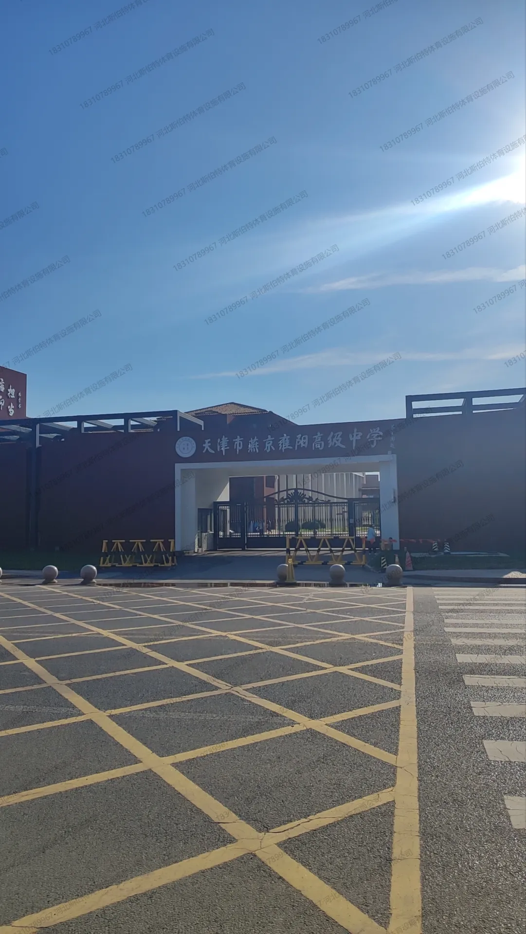 学校正门全景：现代风格校门建筑，前方广场划有黄色网格禁停标线