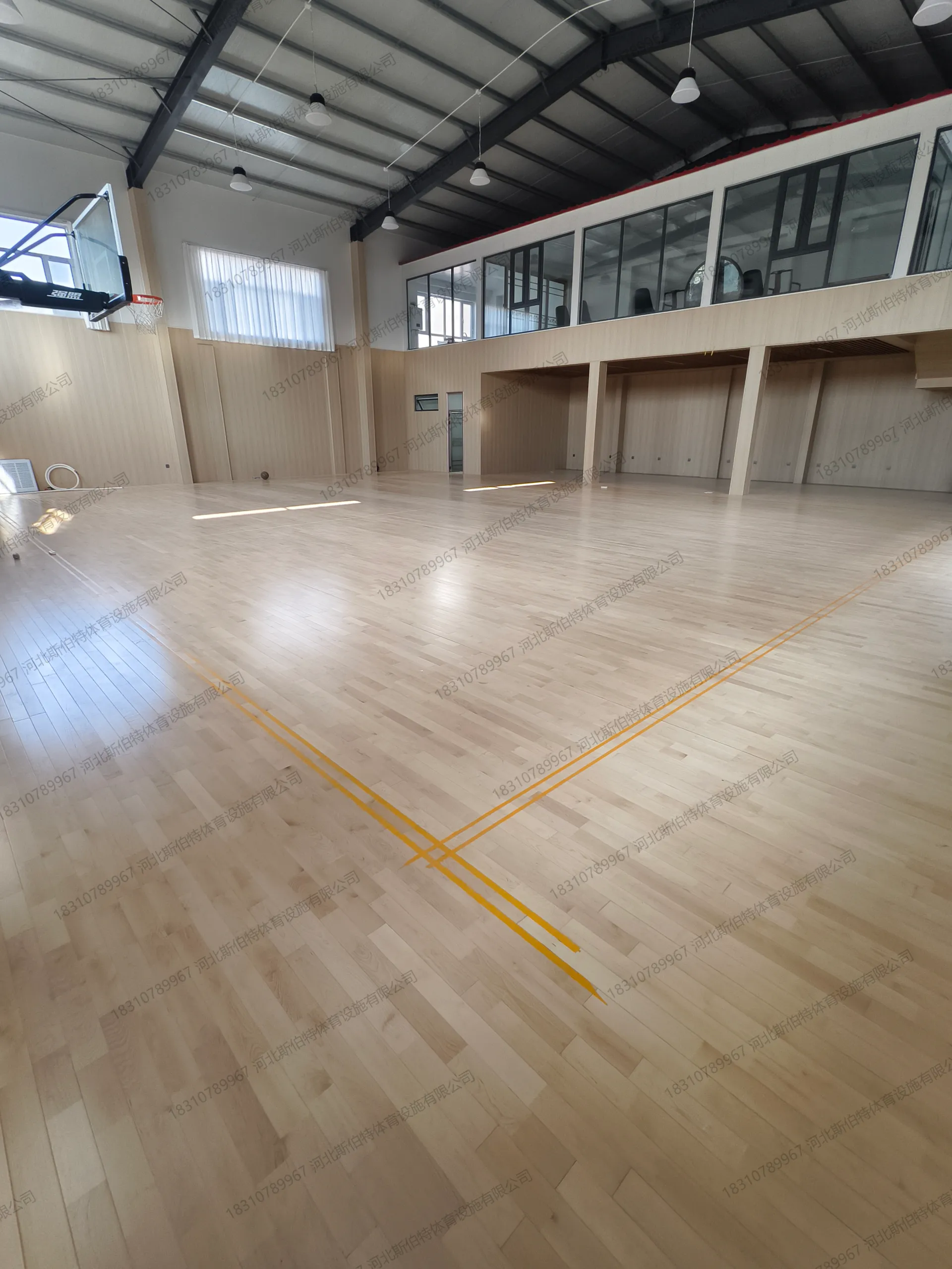 完工空场：枫桦木AB级地板铺满，黄色标线清晰，强盟篮球架就位