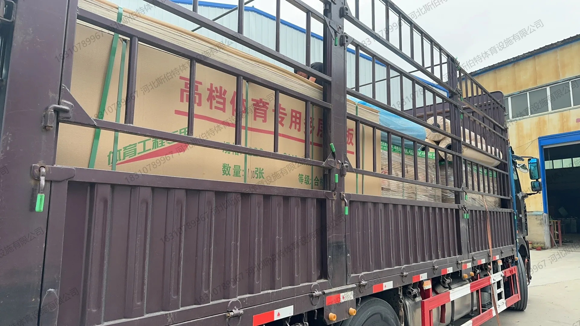 材料进场：货车卸货，包装箱印"高档体育专用多层板"