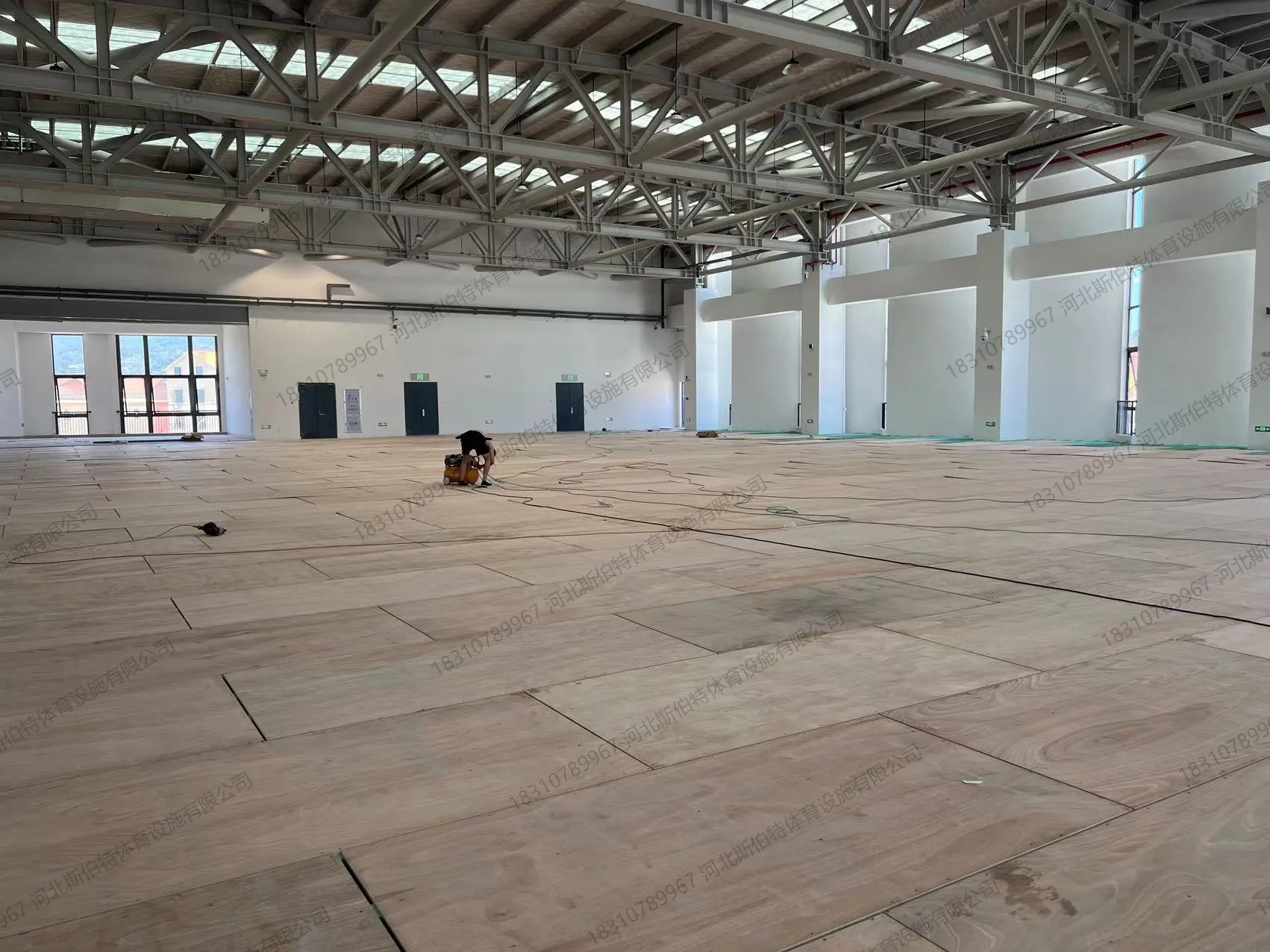 打磨收尾：工人用打磨机处理地板表面，准备上漆
