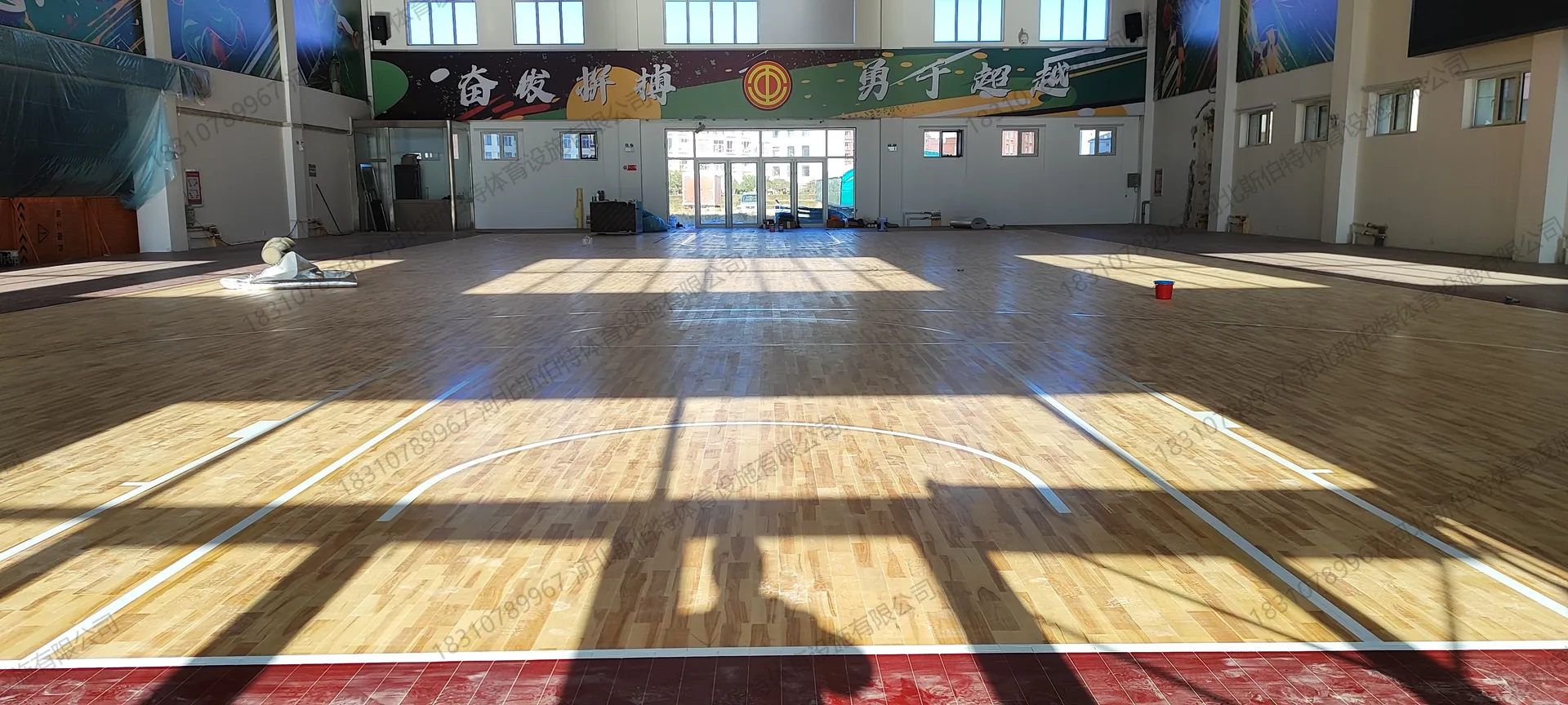 完工全景:篮球馆全貌,地板铺满,标线清晰,横幅标语