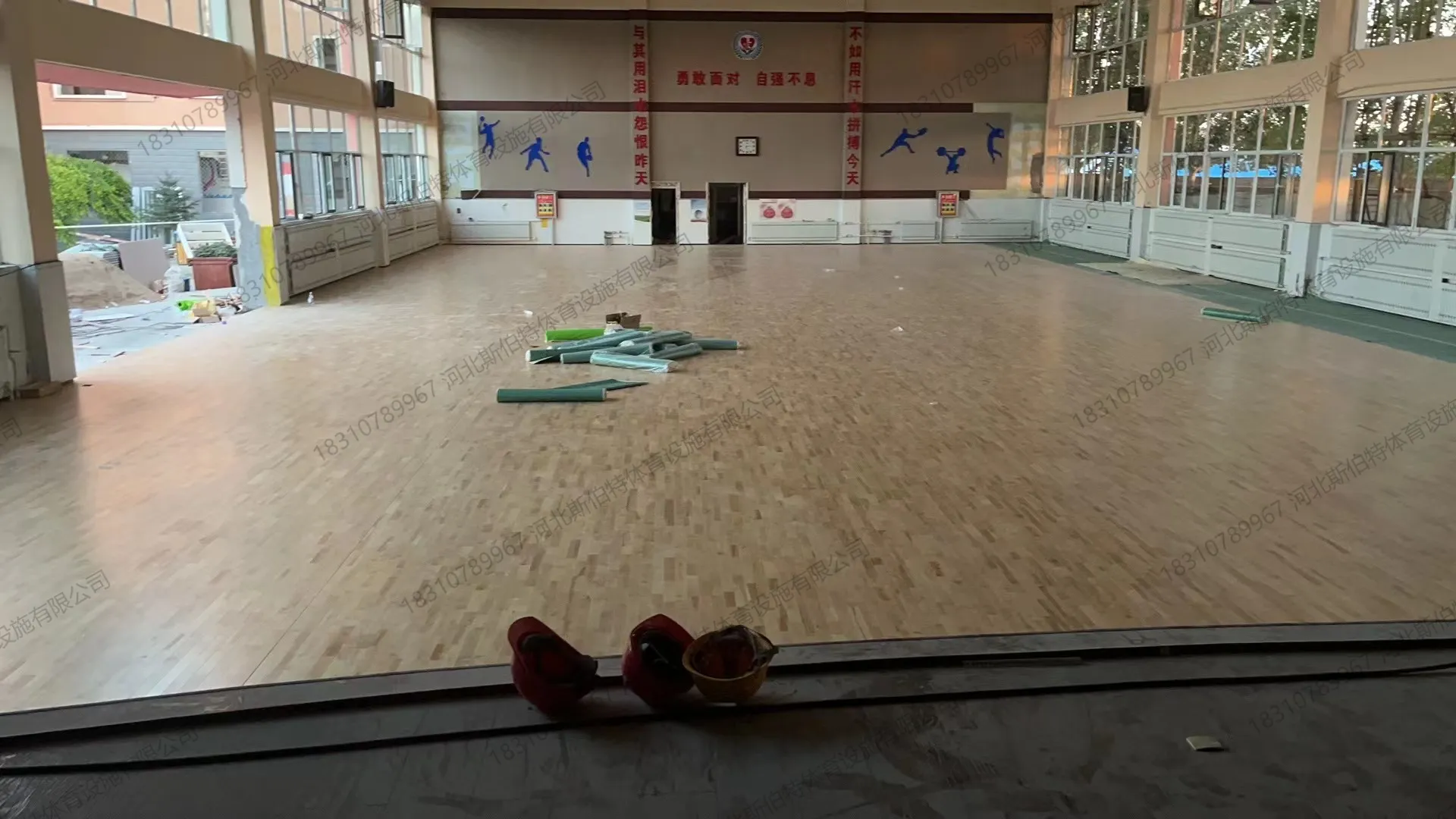 低角度视角,前景安全帽,背景墙运动剪影和励志标语