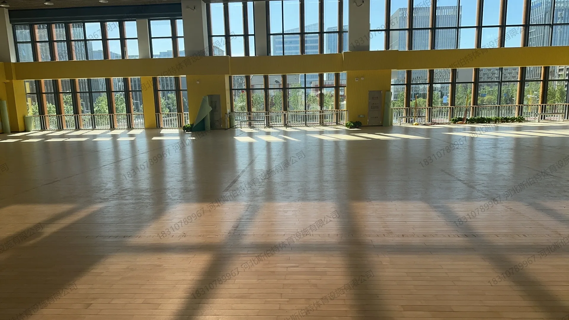 完工实景：木地板铺装完成，玻璃幕墙采光，标线清晰