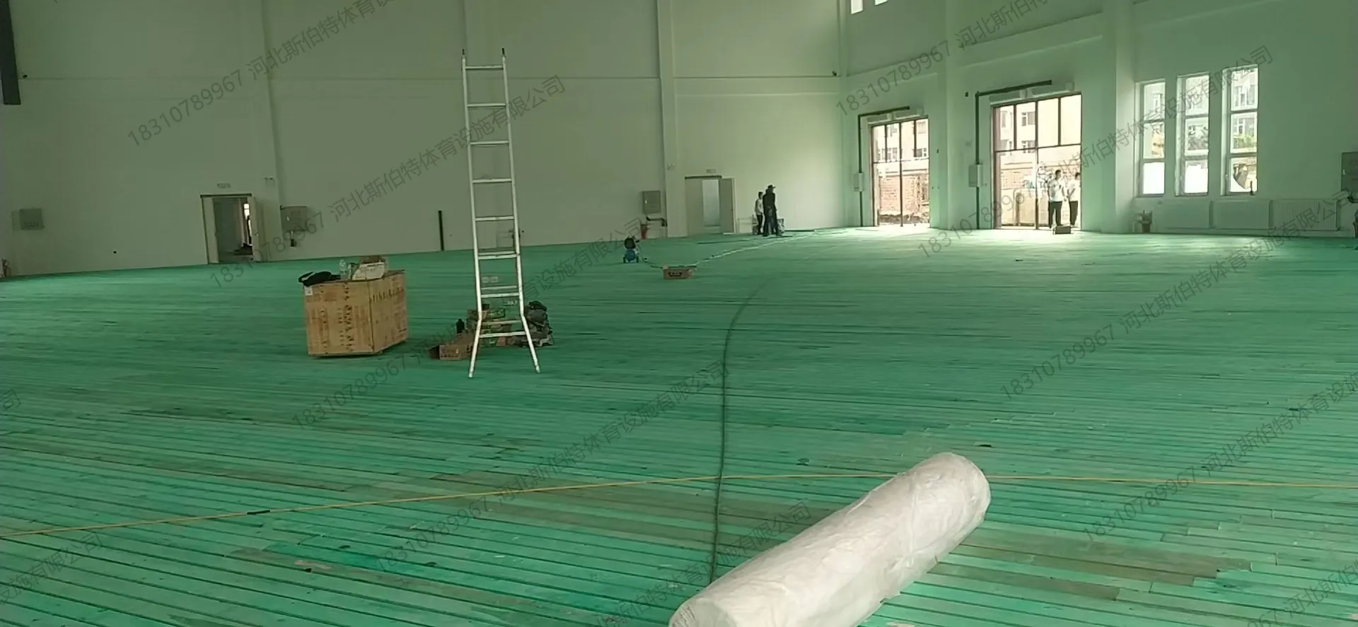 地板斜铺完成：面板以45度角斜向铺装，表面绿色保护膜