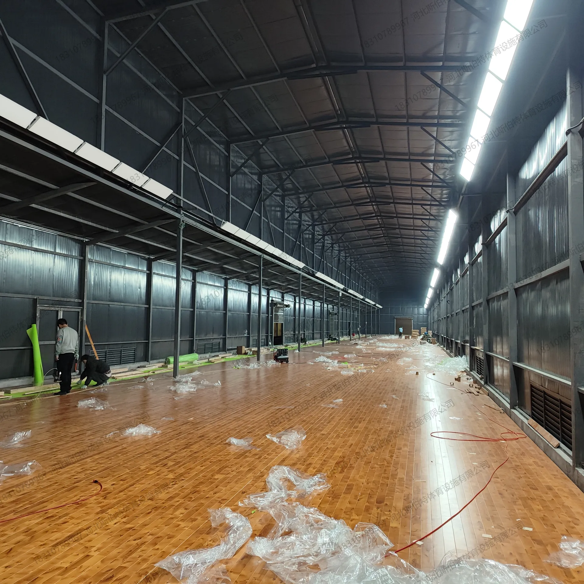 面板铺装阶段:枫桦木面板企口拼接,工人施工中