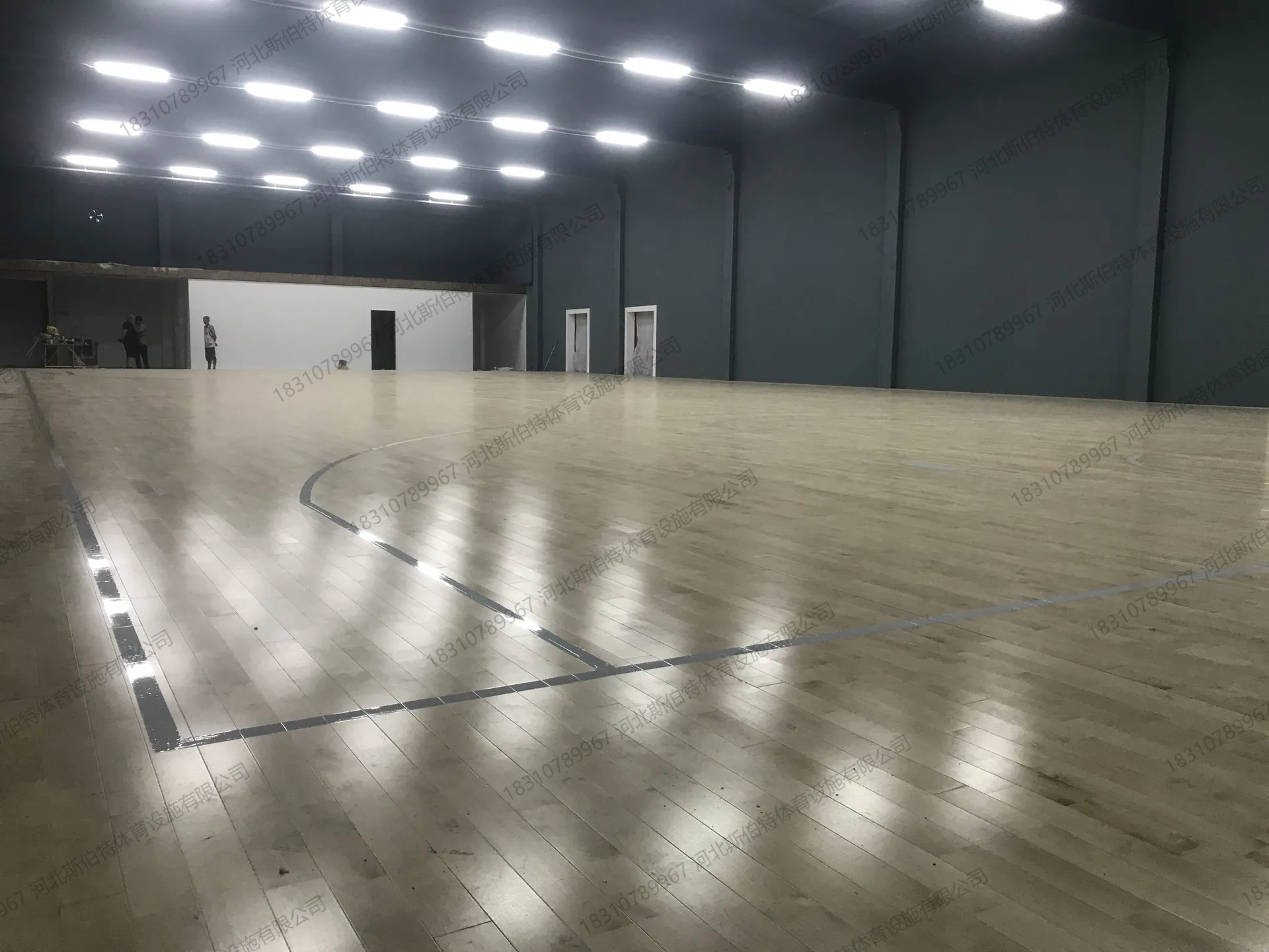 完工实景：枫桦木AB级原木色地板铺装完成，浅木色纹理清晰，篮球场标线白色清晰