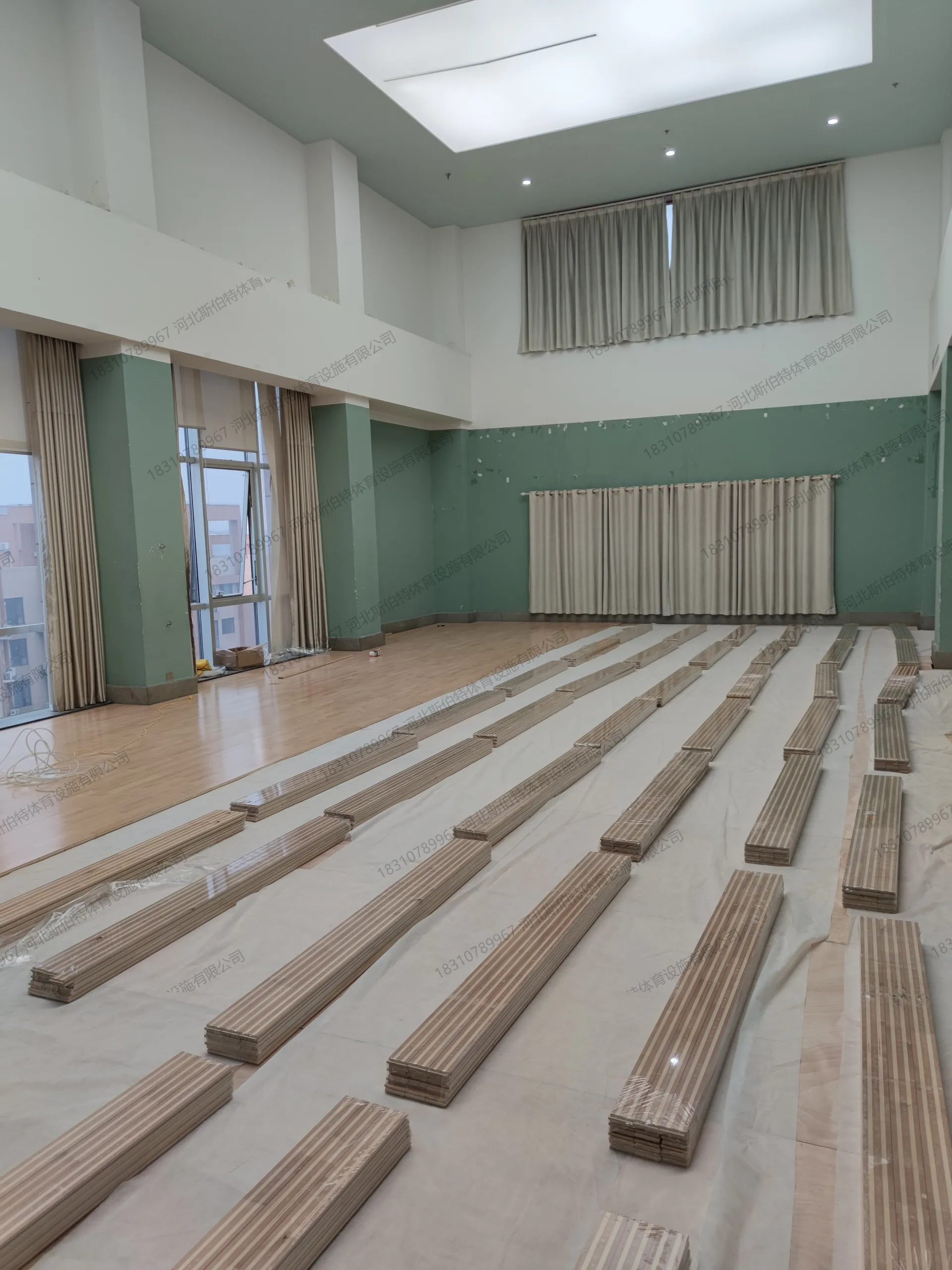 施工过程：双龙骨网格结构铺设完成，减震垫块就位，面板待铺，板材堆放整齐